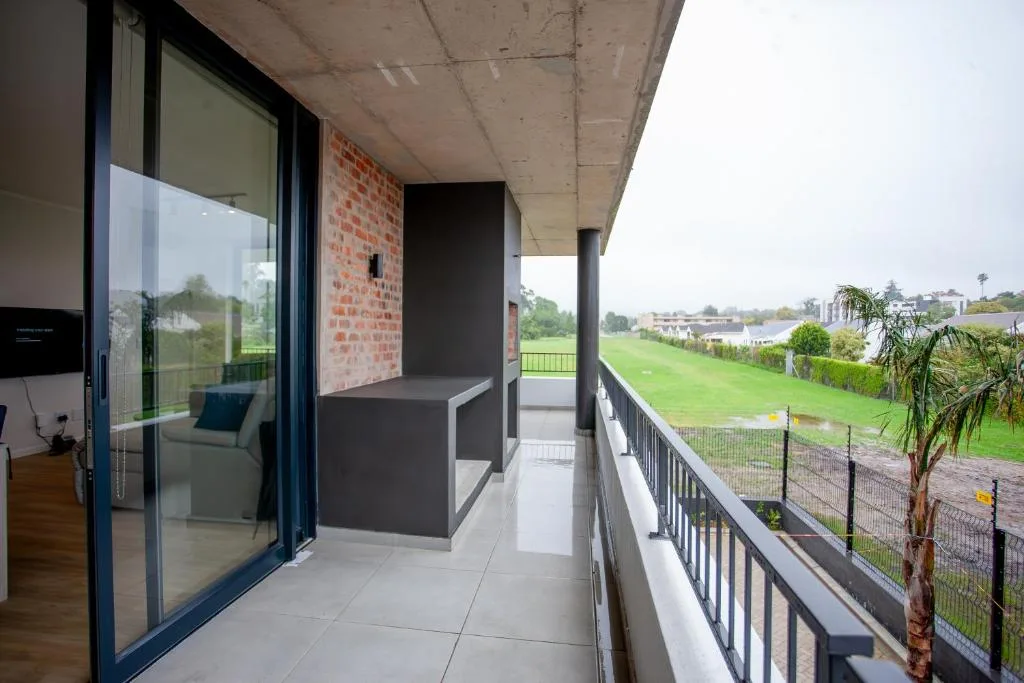 Modern balcony with railing overlooking green fields and distant landscape
