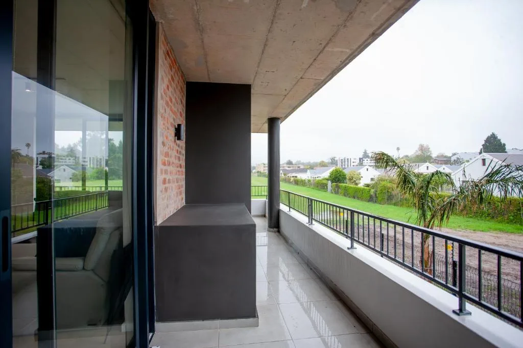 Spacious covered balcony with black railing overlooking residential town landscape