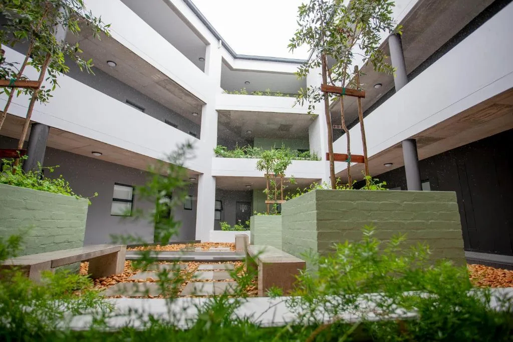 Modern white apartment building with central courtyard, lush greenery, and wooden planters