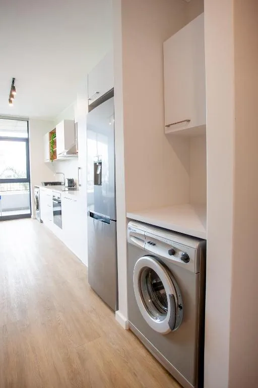 Modern kitchen with white cabinetry, stainless steel appliances, and washing machine