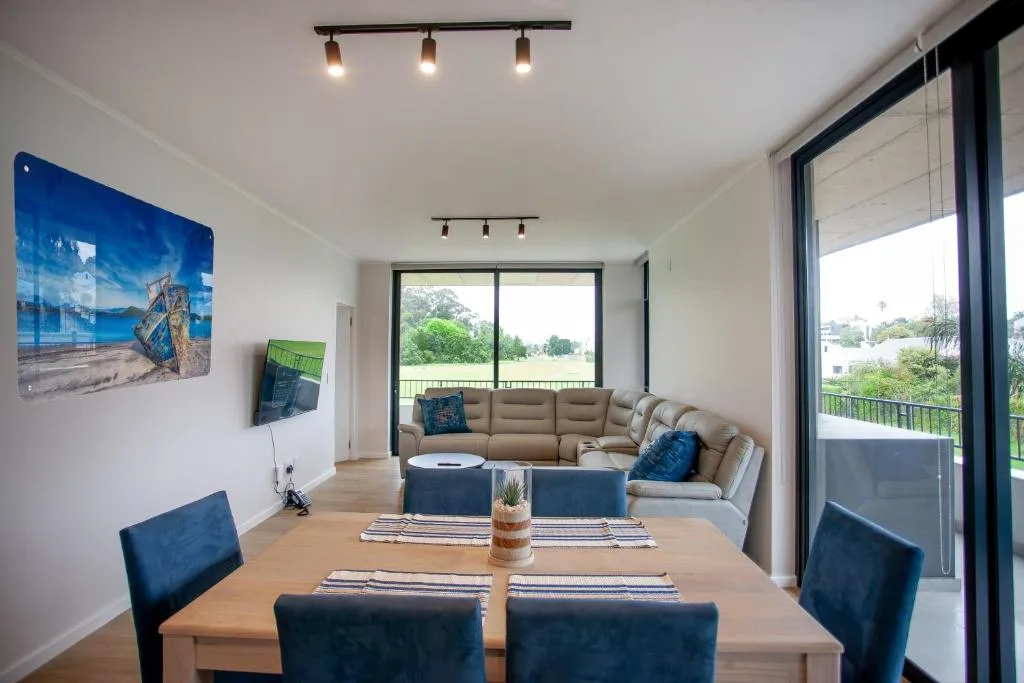 Modern lounge with beige sectional sofa and blue accents overlooking garden
