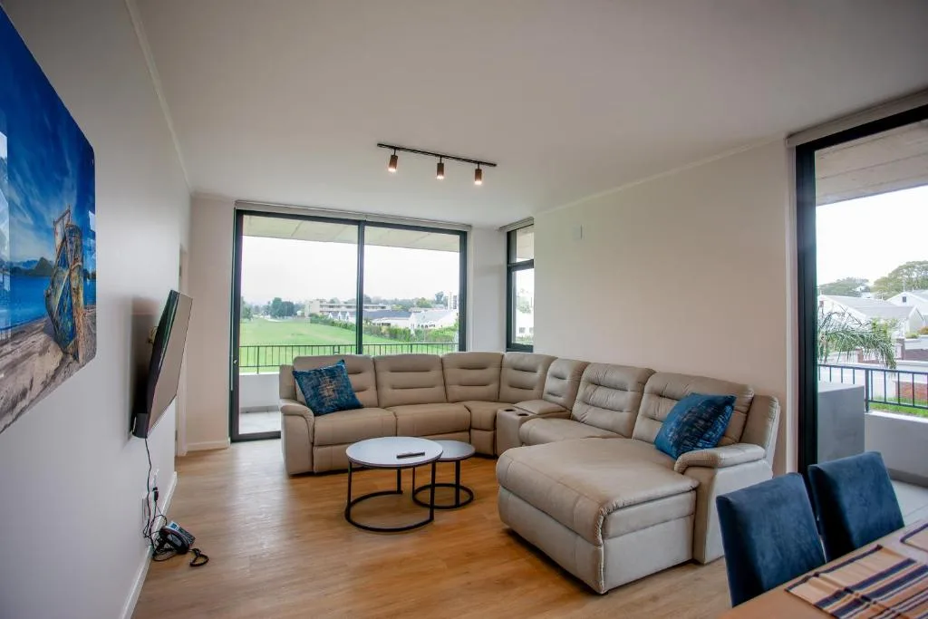 Spacious lounge with beige sectional sofa, round coffee tables, and panoramic views