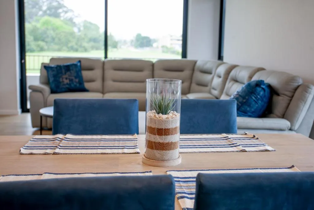 Open-plan lounge with beige sectional sofa and large windows overlooking gardens