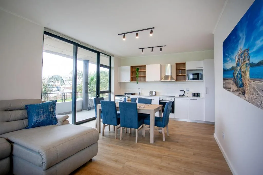 Open-plan lounge with gray sofa and dining area with blue chairs