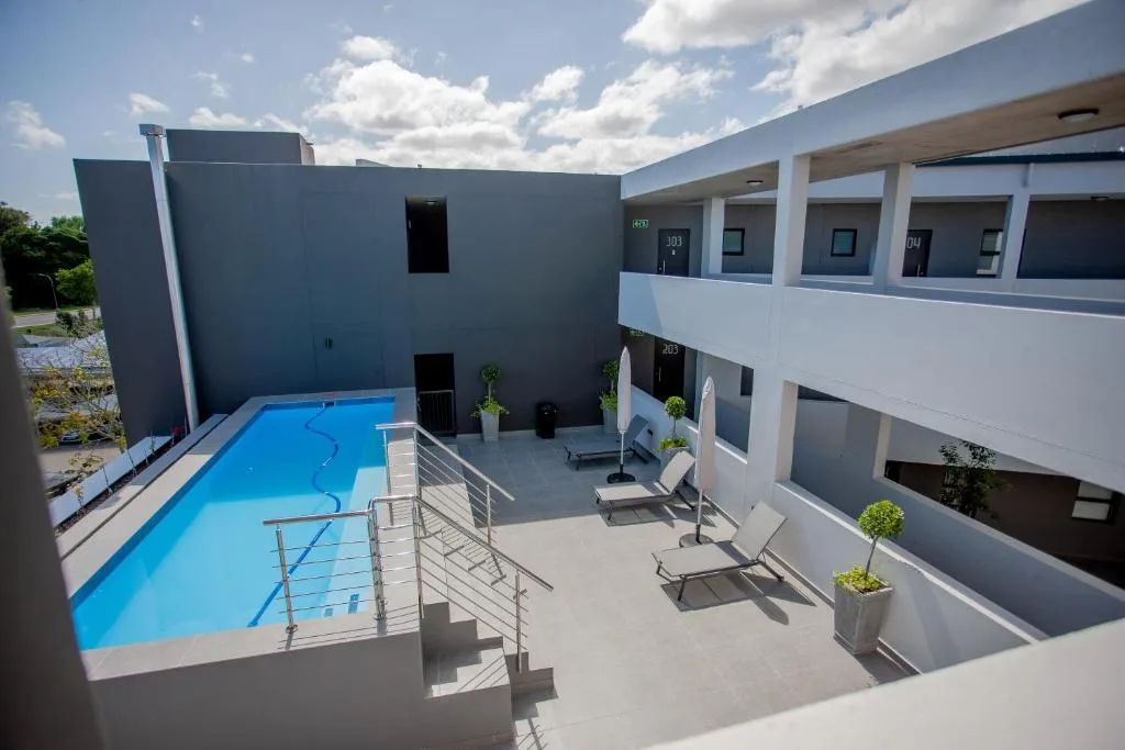 Bright blue swimming pool with metal railings in modern courtyard complex