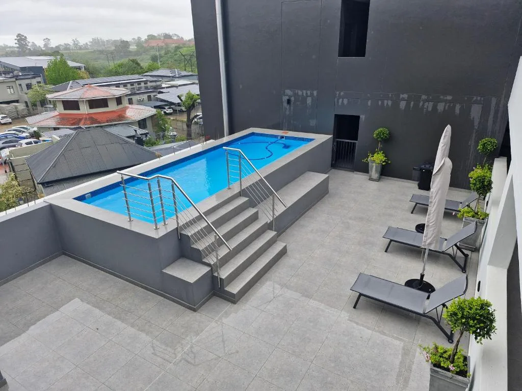 Modern swimming pool with loungers and surrounding patio area overlooking gardens