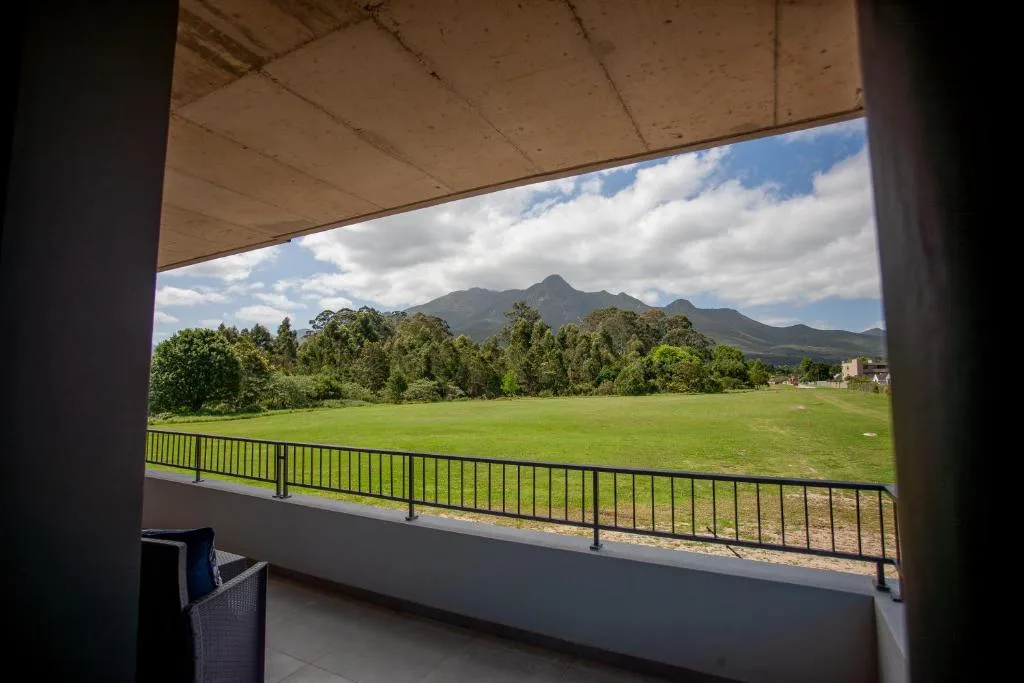 Scenic mountain vista with lush green meadows and tree-lined landscape from balcony