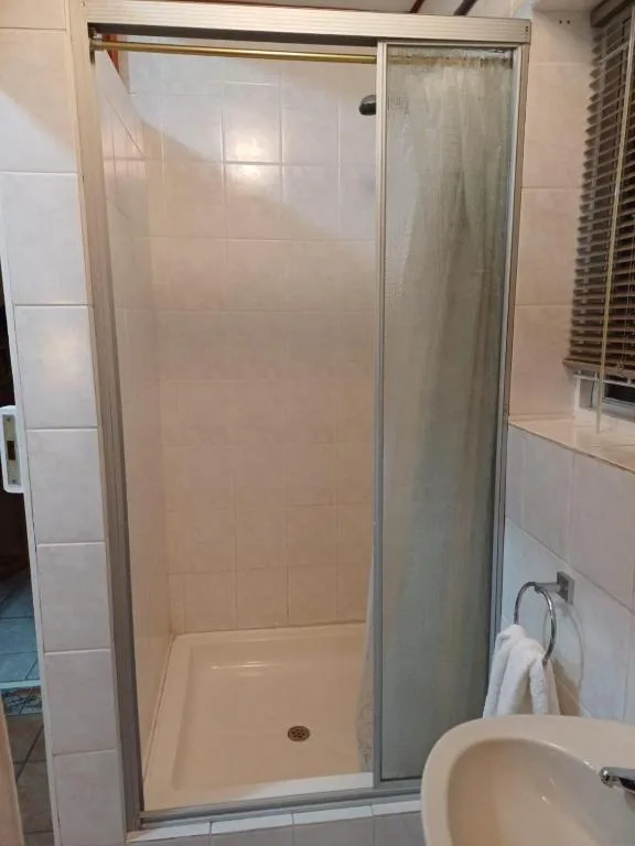 Shower enclosure with glass door and white tile walls in modern bathroom