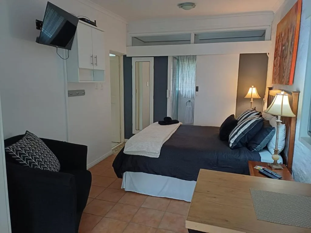 Spacious bedroom with double bed, armchair, bedside lamps, and en-suite access
