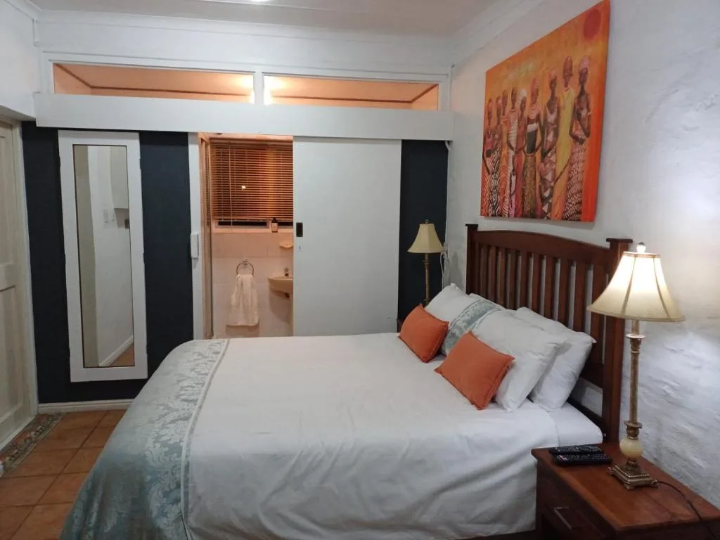 Bright bedroom with wooden bed frame, white linens, and orange accent pillows