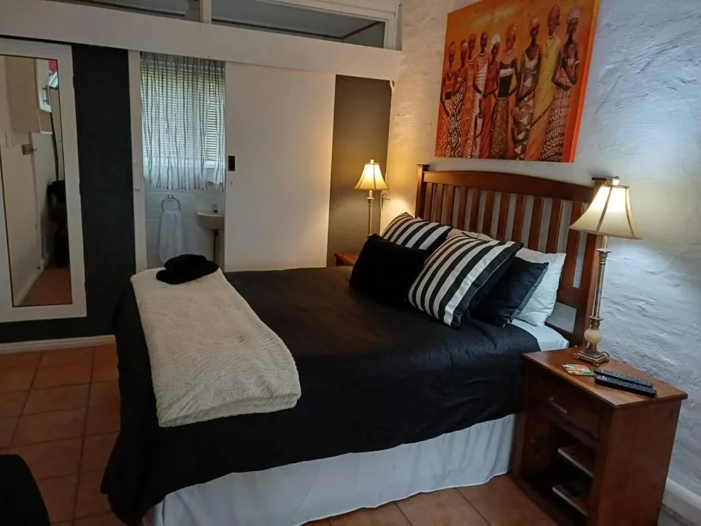 Spacious bedroom with wooden bed frame, striped pillows, and African artwork