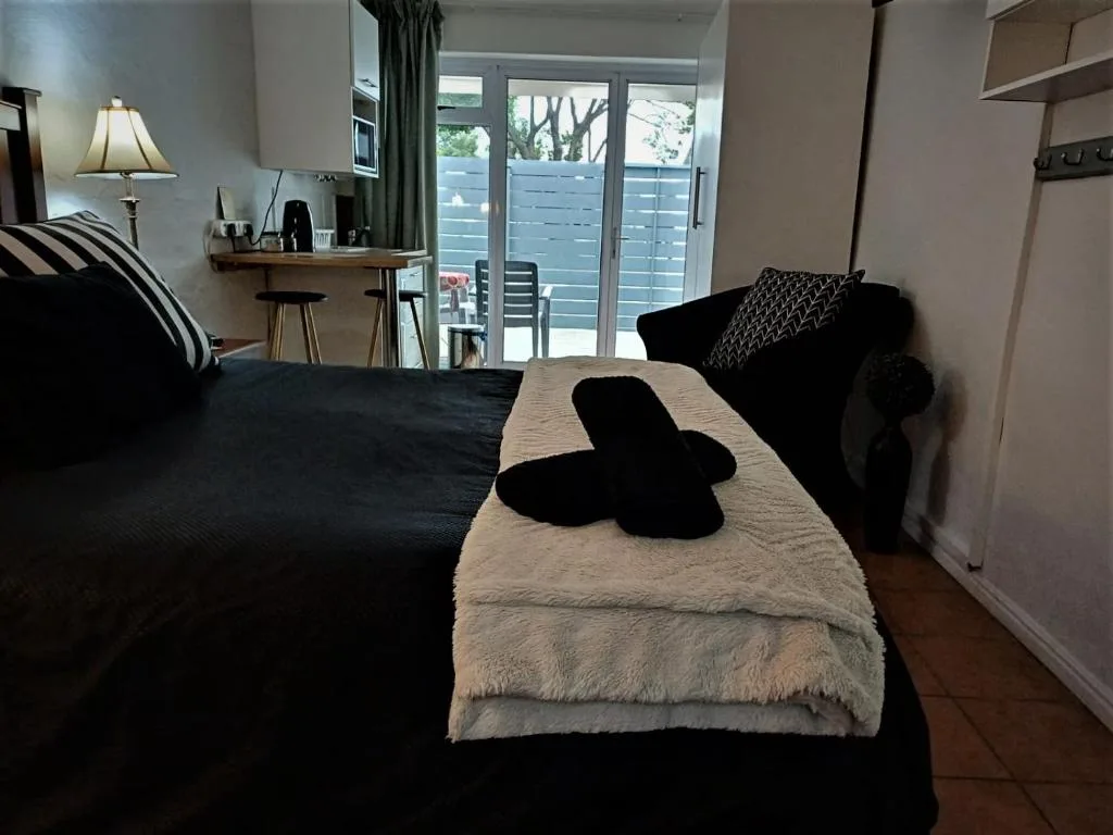 Spacious bedroom with black bed, cream throw, desk, and deck access doors