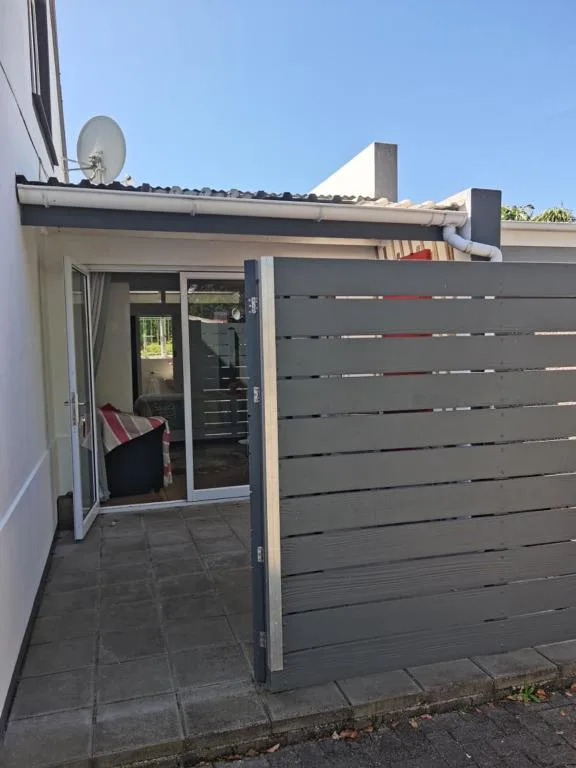Modern apartment entrance with dark slatted gate and paved patio area