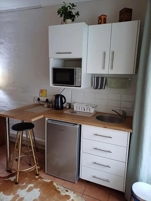Compact kitchen with white cabinetry, wooden countertop, and bar seating