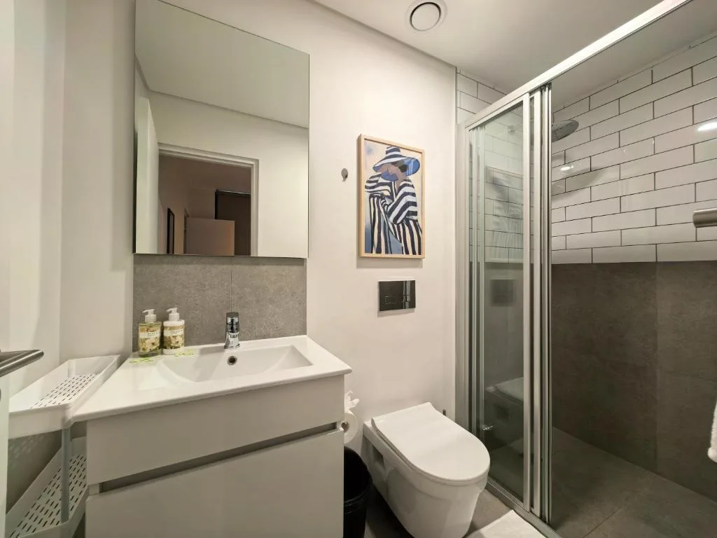 Modern bathroom with white vanity, toilet, and glass-enclosed shower enclosure