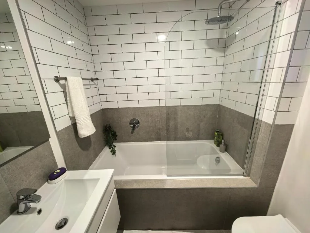 Modern bathroom with subway tile walls, gray half-tile feature, and soaking tub