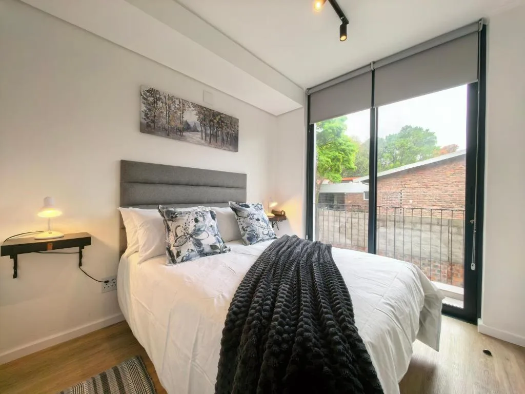 Modern bedroom with queen bed, gray headboard, and sliding glass doors