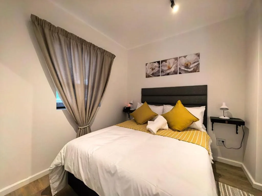 Bright bedroom with double bed, yellow cushions, and natural light