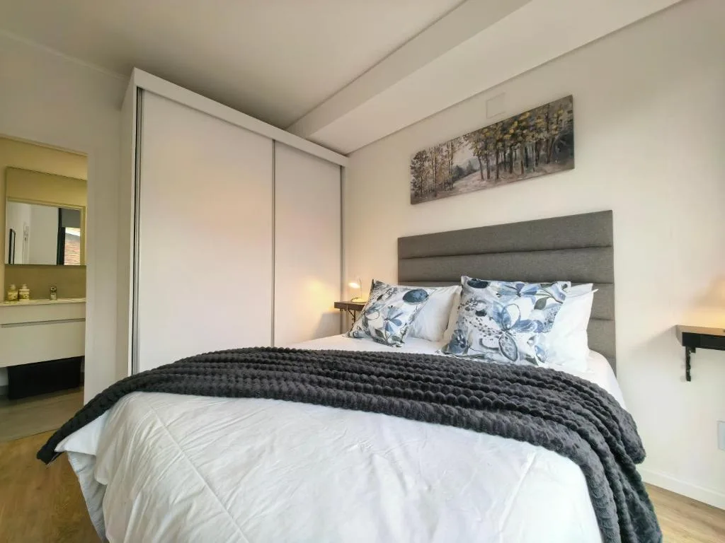 Spacious bedroom with queen bed, gray headboard, and built-in wardrobe