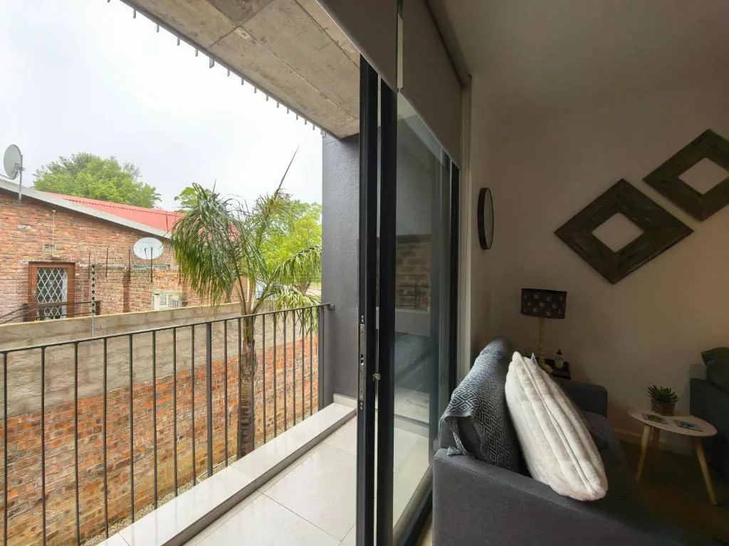 Modern balcony with metal railing overlooking brick buildings and garden