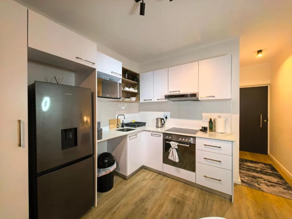 Modern kitchen with white cabinetry, black stove, and stainless steel refrigerator