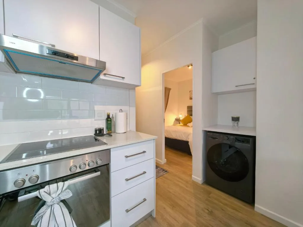 Modern white kitchen with stainless steel appliances and bedroom view
