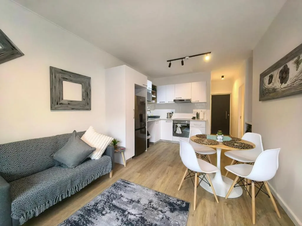 Modern open-plan lounge with sofa, dining table, and integrated kitchen area