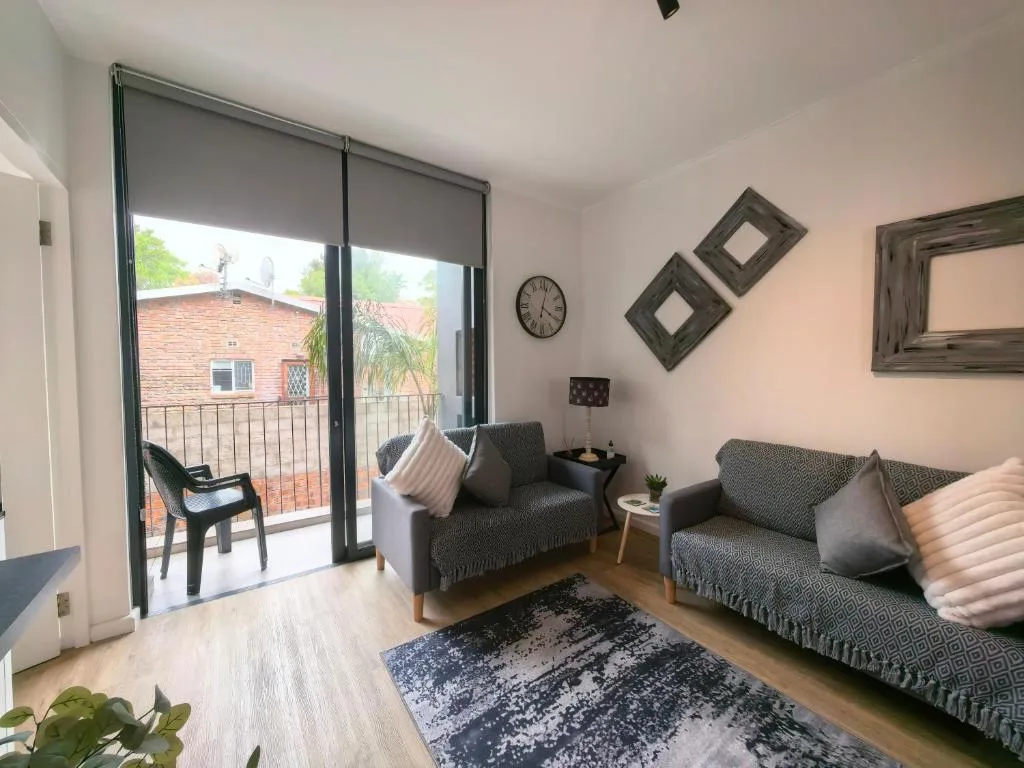Bright lounge with gray sofas, wooden floors, and deck access through glass doors