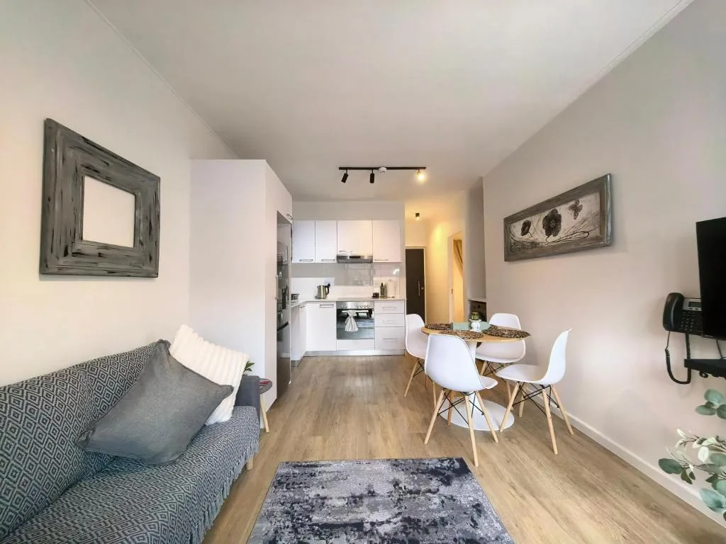 Open-plan lounge with sofa, dining table, and kitchen area beyond