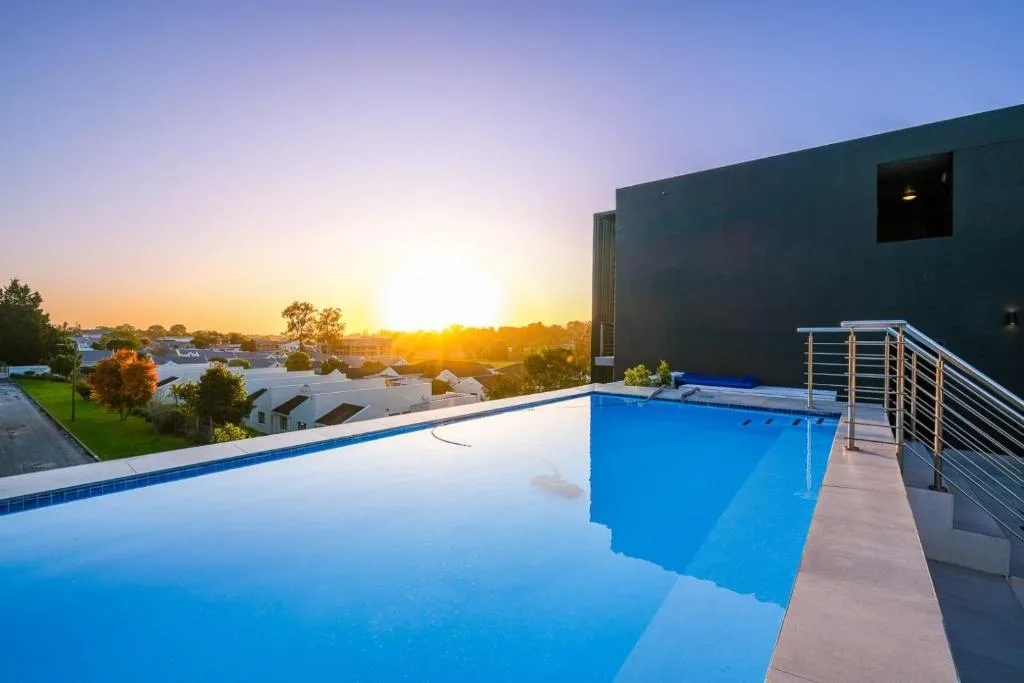 Illuminated swimming pool at sunset with town views and modern architecture