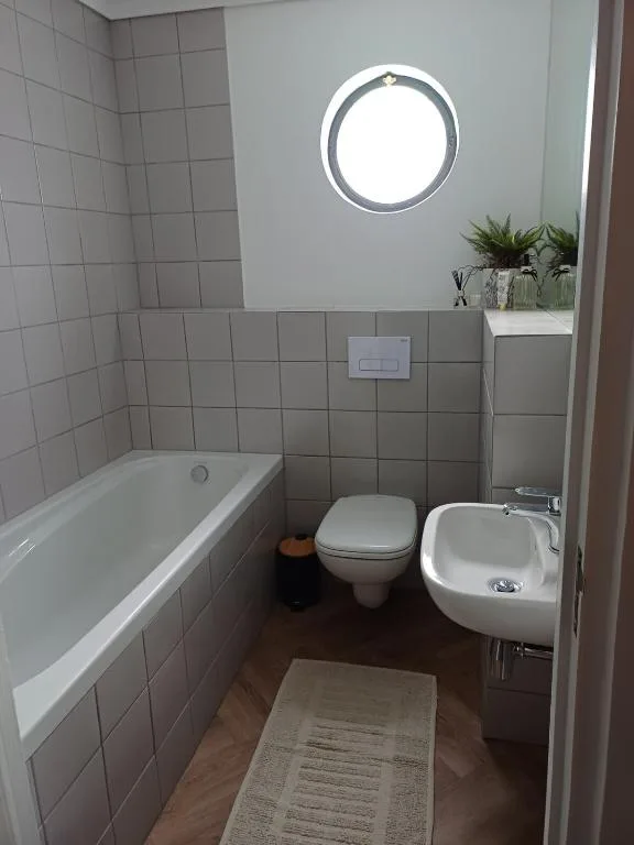 Modern bathroom with bathtub, toilet, sink, and round porthole window