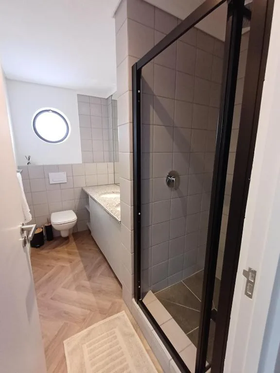 Modern bathroom with walk-in shower, toilet, and circular mirror light