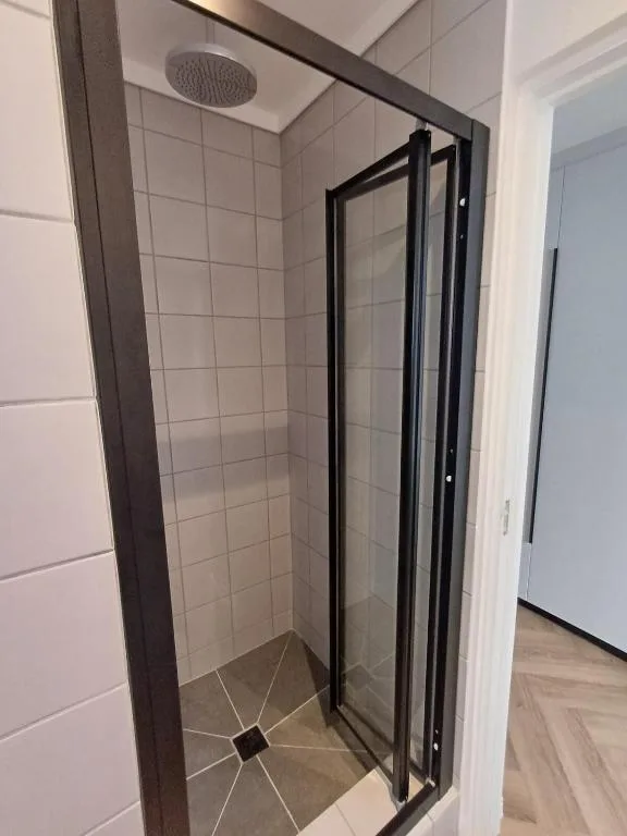 Modern shower enclosure with black frame and overhead rainfall showerhead
