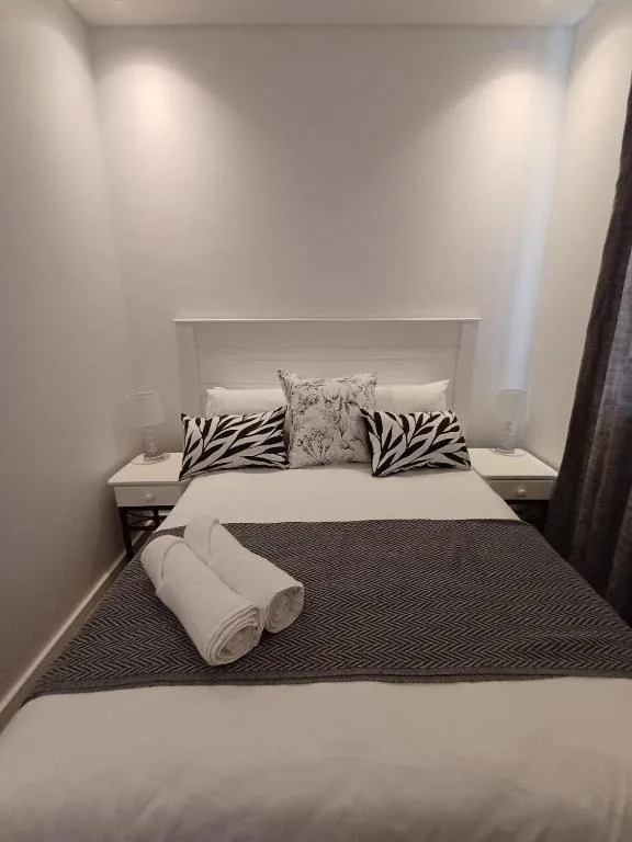 Modern bedroom with white bed, zebra-print pillows, rolled towels