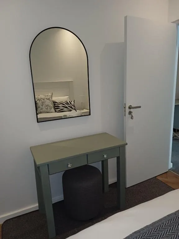 Bedroom vanity with arched mirror and sage green desk