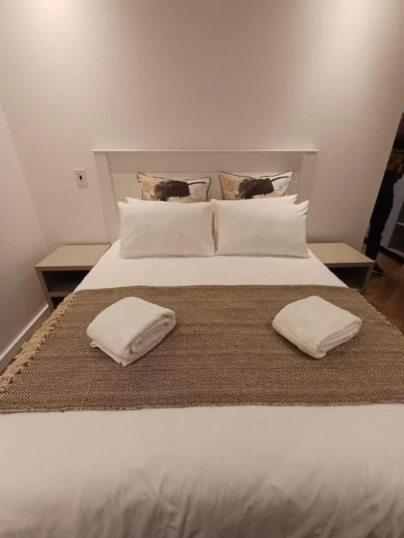 Modern bedroom with queen bed, white linens, and fresh towels