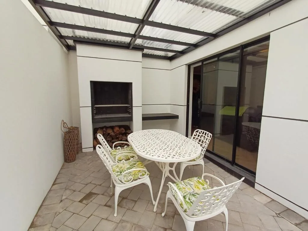 Covered outdoor patio with white dining table and chairs, fireplace