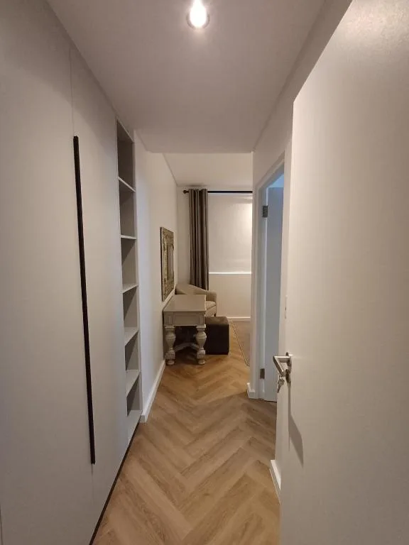 Modern hallway with herringbone flooring and built-in white shelving units
