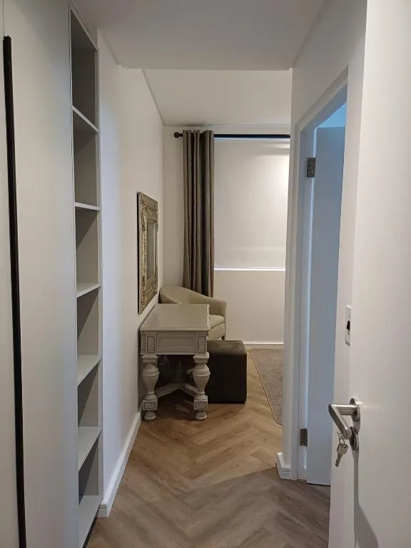 Narrow hallway with built-in shelving, small table, and natural light from window