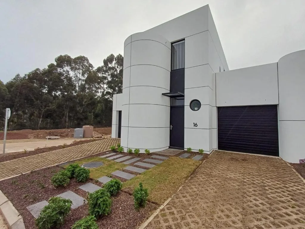 Modern white curved apartment building with black entrance door and garage