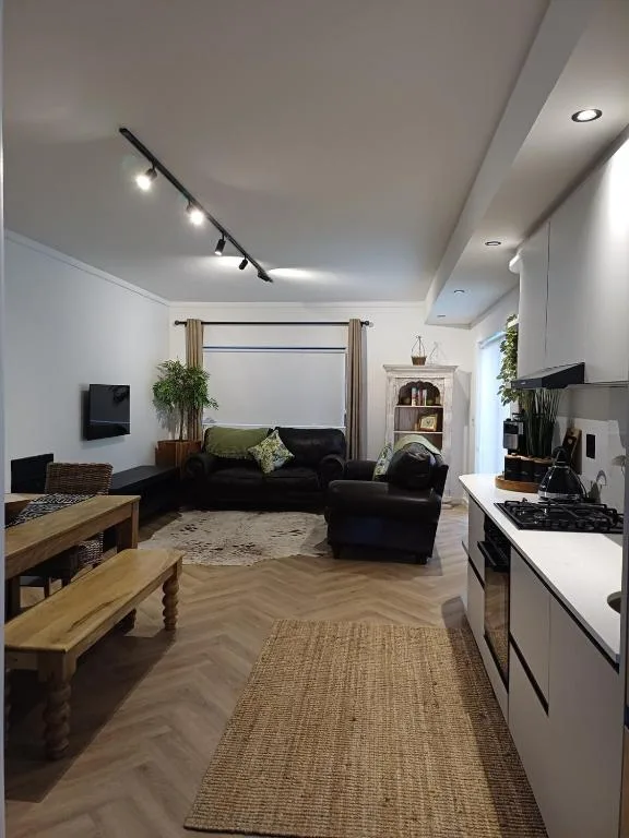 Open-plan lounge with black sofa, wooden furniture, modern lighting fixtures