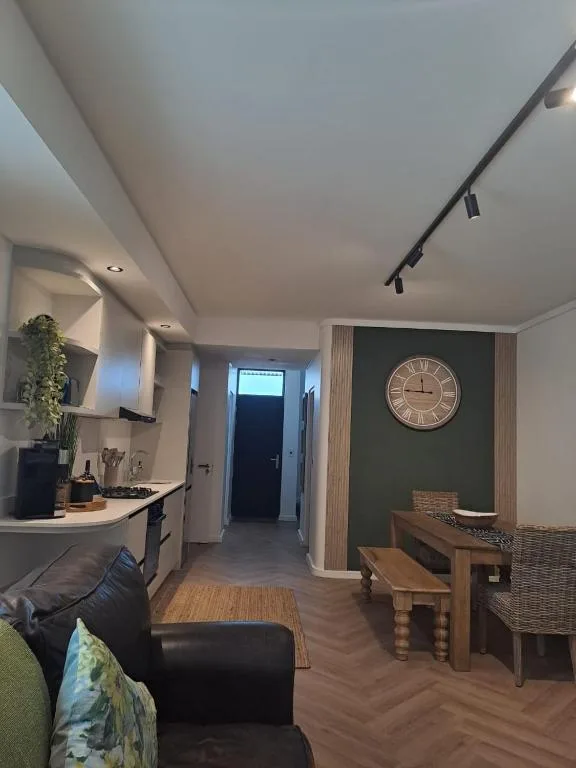 Open-plan lounge and kitchen area with black sofa and wooden dining table