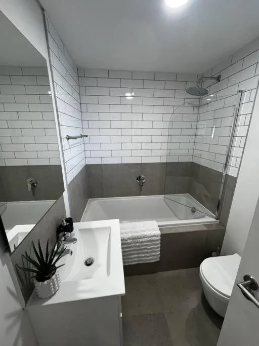 Modern bathroom with white subway tiles, bathtub, and vanity sink