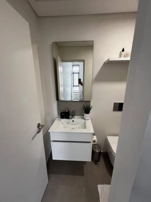 Modern bathroom with white vanity sink and mirror, neutral walls and dark floor
