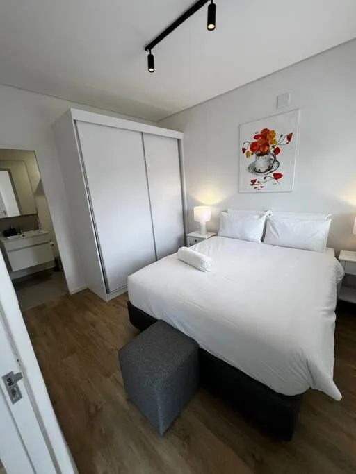 Bright bedroom with queen bed, white bedding, modern wardrobe and wall art