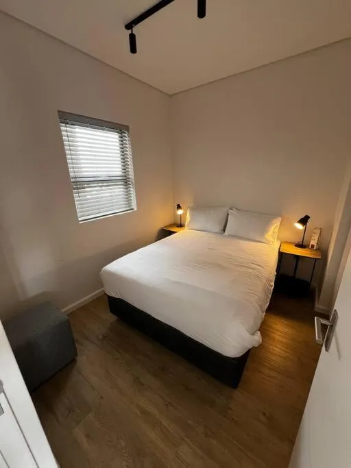 Minimalist bedroom with queen bed, warm lighting, wooden floor