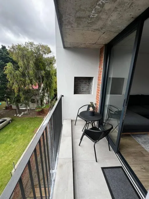 Small balcony with two black chairs overlooking green garden lawn
