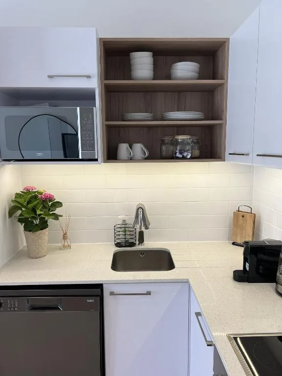 Modern kitchen with white subway tiles, open shelving, and microwave