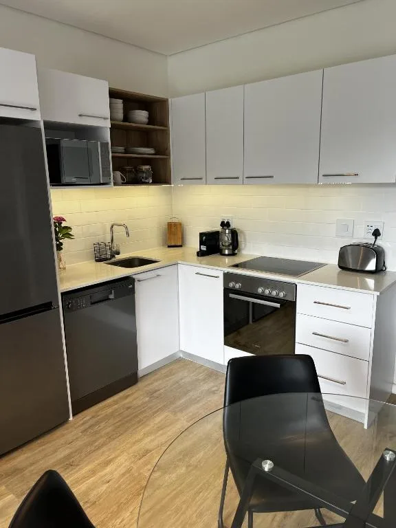 Modern white kitchen with black appliances and warm lighting