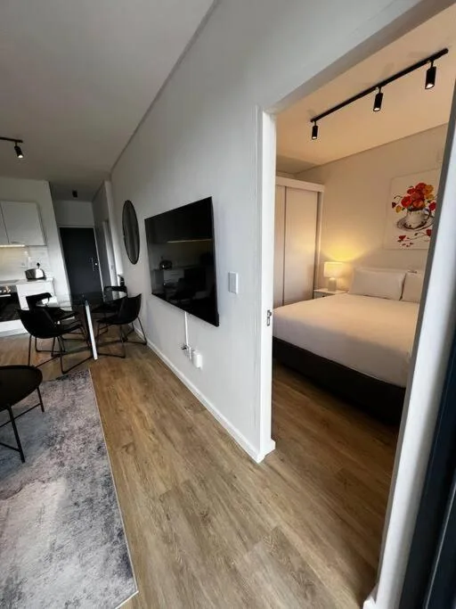 Modern lounge with wall-mounted TV and open bedroom view beyond